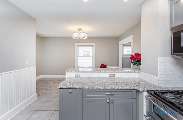 kitchen featuring kitchen peninsula, gray cabinets, and light stone counters