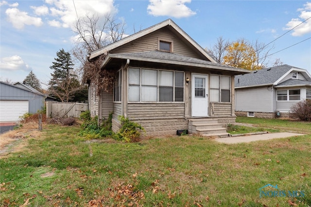 bungalow featuring a front yard and an outdoor structure