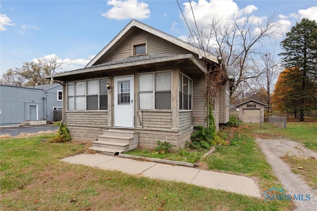 bungalow-style home featuring a garage, an outdoor structure, and a front yard