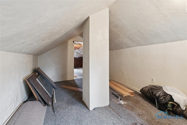 bonus room featuring a textured ceiling, carpet floors, and lofted ceiling