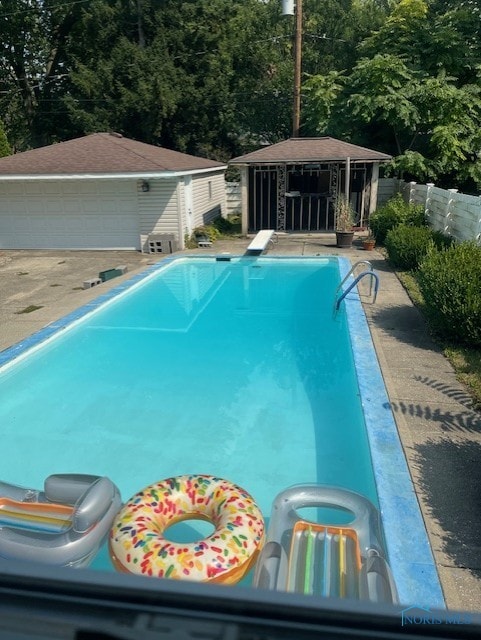 view of pool featuring a diving board and an outdoor structure