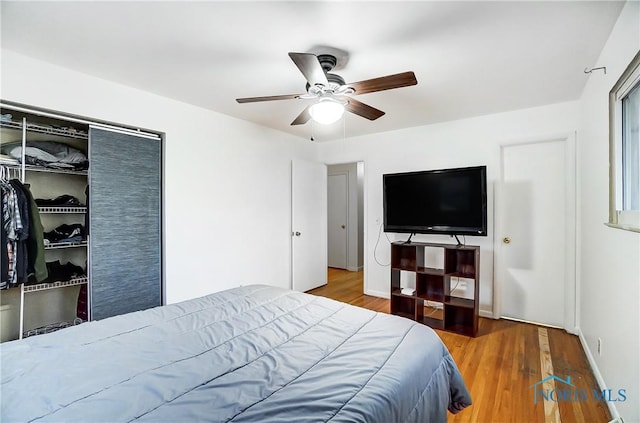 bedroom featuring hardwood / wood-style flooring, ceiling fan, and a closet