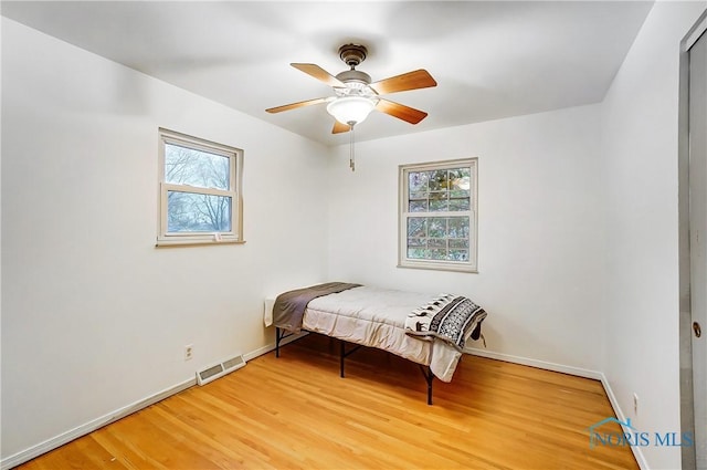 bedroom with multiple windows, hardwood / wood-style flooring, and ceiling fan