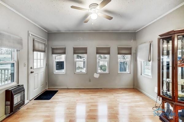 foyer with heating unit, ceiling fan, crown molding, and light wood-type flooring