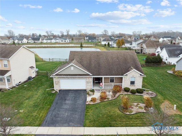 view of front of home featuring a porch, a water view, a front yard, and a garage