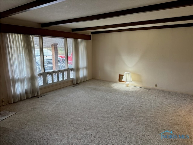 unfurnished room with beamed ceiling and carpet flooring