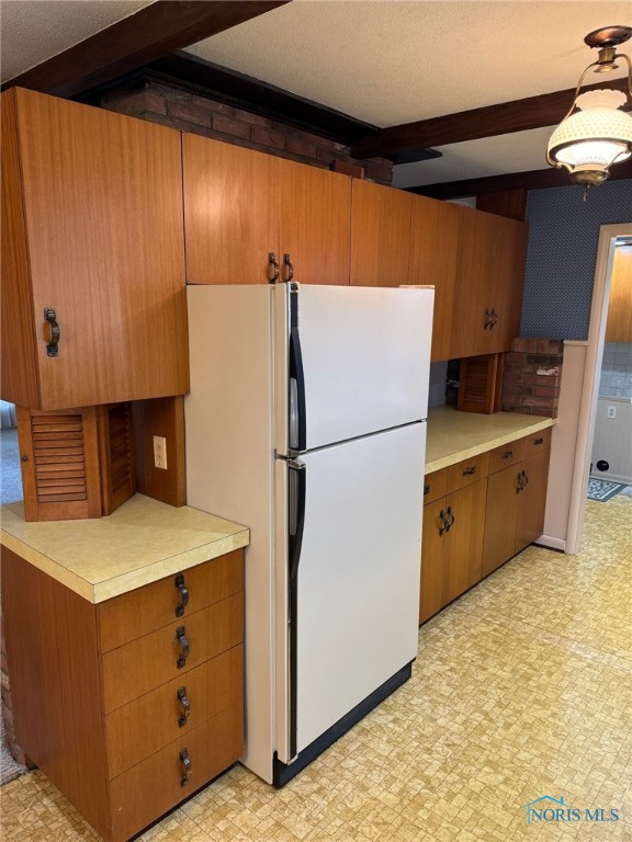 kitchen with beamed ceiling, white fridge, and a textured ceiling