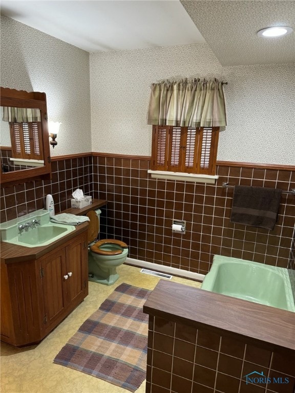 bathroom featuring vanity, toilet, and tile walls