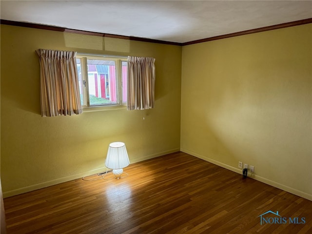 unfurnished room featuring ornamental molding and dark wood-type flooring