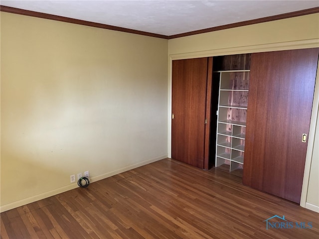 unfurnished bedroom with a closet, dark hardwood / wood-style flooring, and crown molding