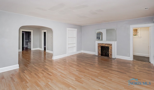 unfurnished living room with built in features and wood-type flooring