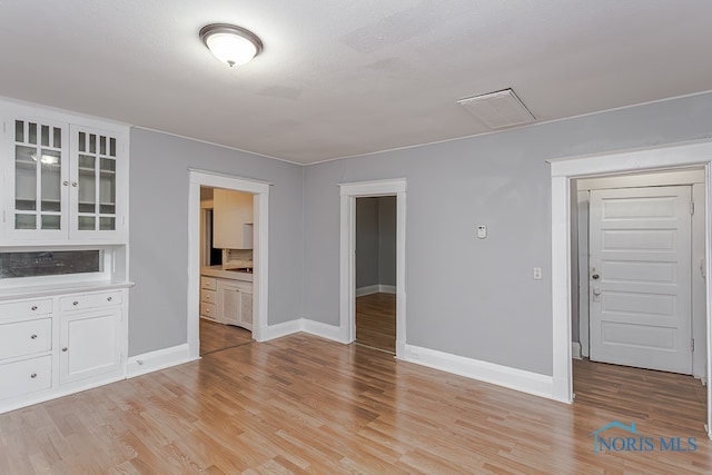 unfurnished living room featuring a textured ceiling and light hardwood / wood-style floors