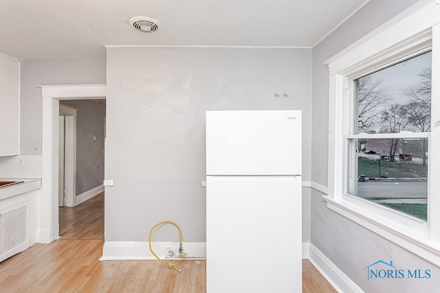 kitchen featuring a textured ceiling, light wood-type flooring, and white fridge