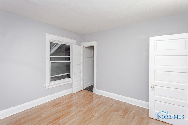 empty room with a textured ceiling and light hardwood / wood-style flooring