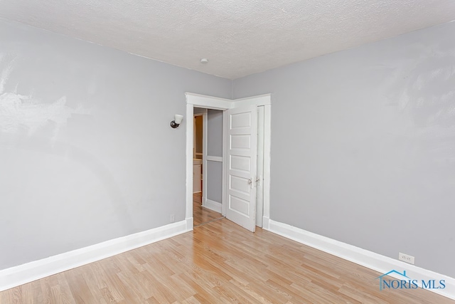 unfurnished room with light hardwood / wood-style floors and a textured ceiling