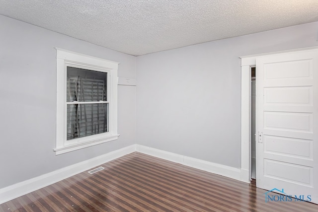 empty room featuring a textured ceiling and dark hardwood / wood-style floors