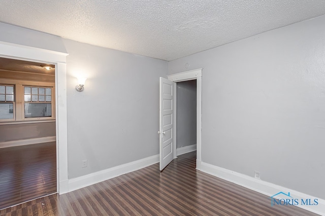 unfurnished room with a textured ceiling and dark hardwood / wood-style floors