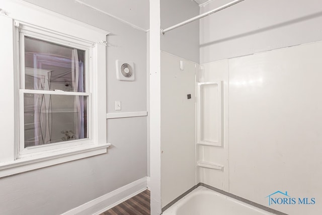 bathroom featuring washtub / shower combination and wood-type flooring