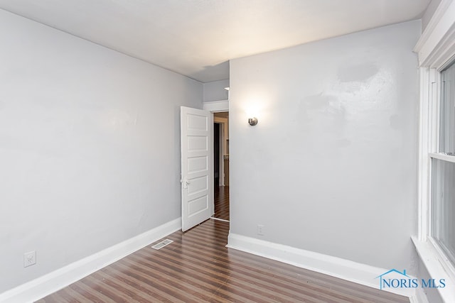 unfurnished room with dark wood-type flooring