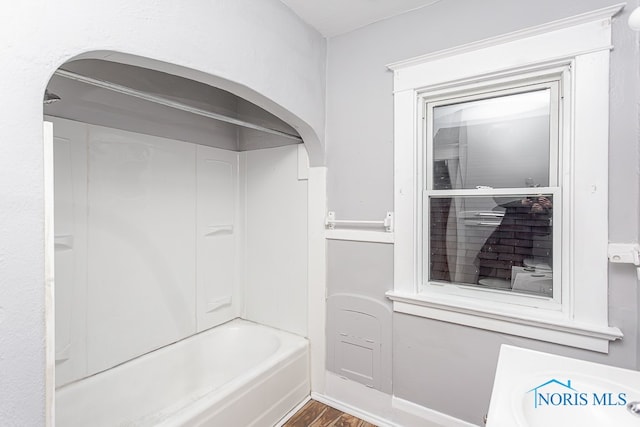 bathroom with wood-type flooring and bathing tub / shower combination