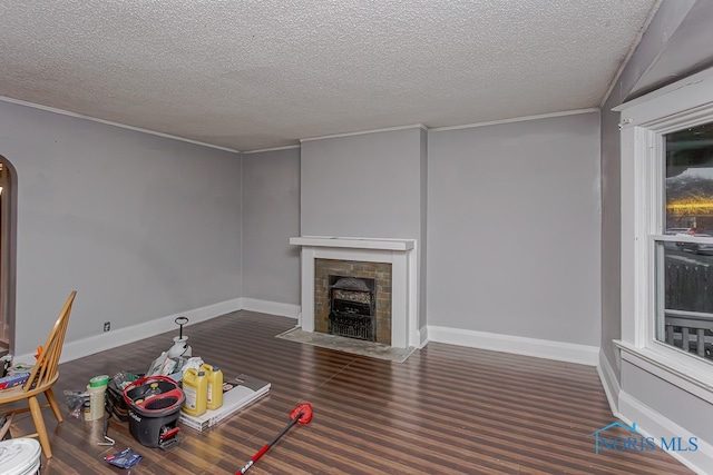 unfurnished living room with dark hardwood / wood-style flooring, ornamental molding, a textured ceiling, and a tile fireplace