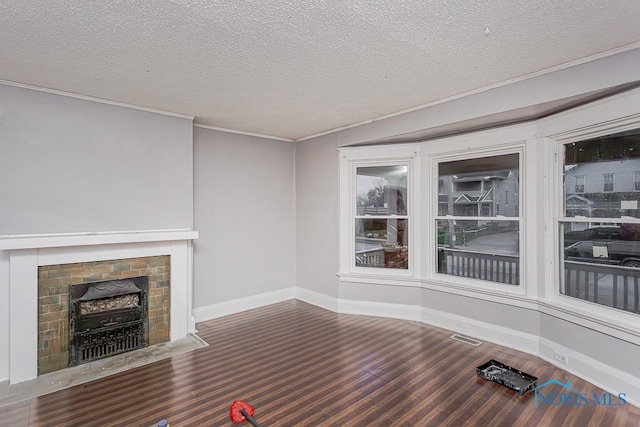 unfurnished living room with a textured ceiling, dark hardwood / wood-style floors, and crown molding