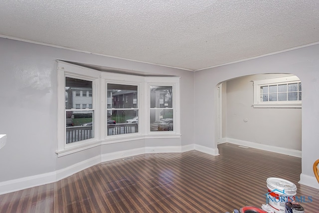 empty room with a textured ceiling, crown molding, and dark hardwood / wood-style floors