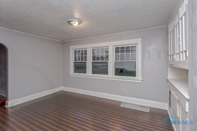 unfurnished room with a textured ceiling, dark hardwood / wood-style floors, and ornamental molding