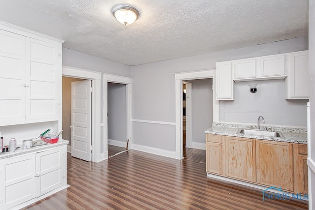 kitchen featuring white cabinetry, sink, dark wood-type flooring, light stone counters, and a textured ceiling