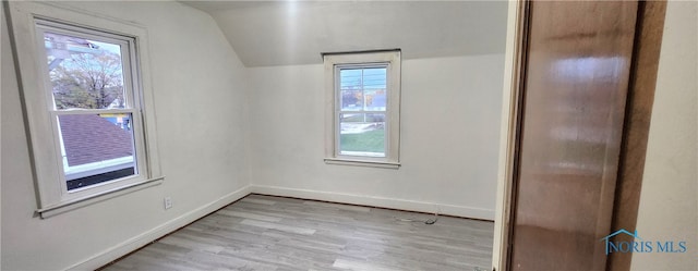 spare room with light hardwood / wood-style floors and lofted ceiling