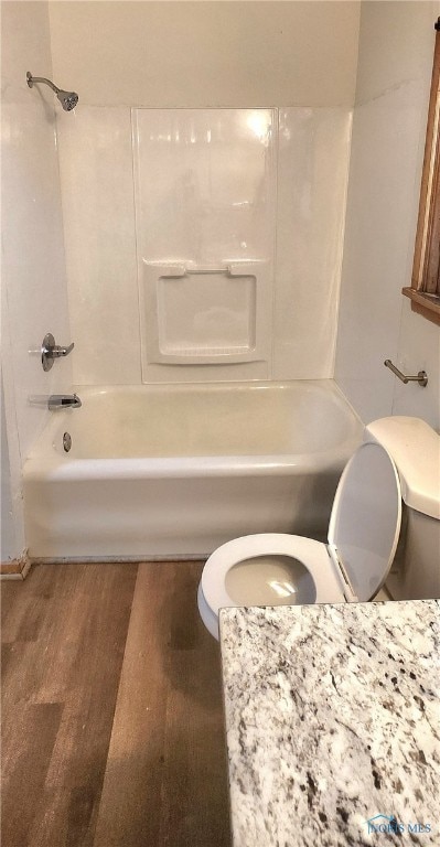 bathroom featuring shower / washtub combination, wood-type flooring, and toilet