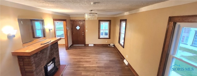 foyer with a textured ceiling, a fireplace, dark hardwood / wood-style floors, and a notable chandelier