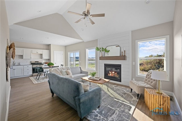 living room featuring ceiling fan, dark wood-type flooring, a large fireplace, and high vaulted ceiling