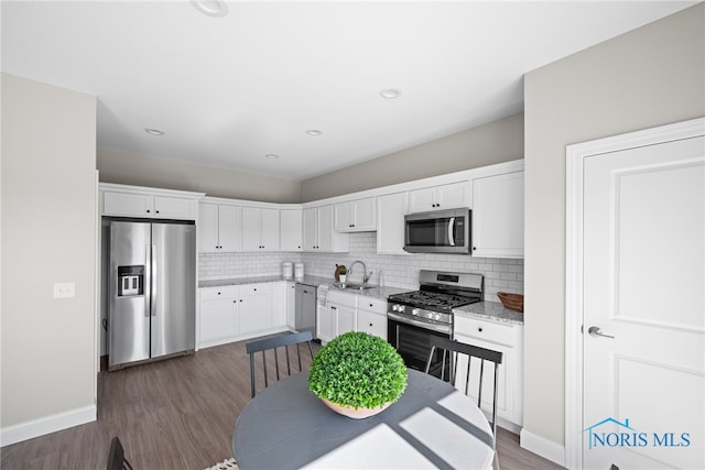 kitchen featuring decorative backsplash, stainless steel appliances, sink, dark hardwood / wood-style floors, and white cabinetry