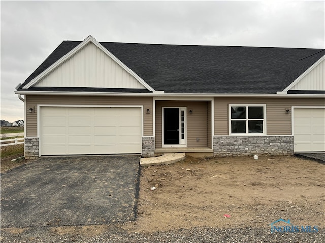 craftsman-style house featuring a garage, a shingled roof, stone siding, driveway, and board and batten siding