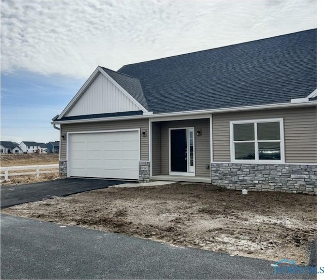 view of front facade featuring an attached garage, stone siding, and driveway