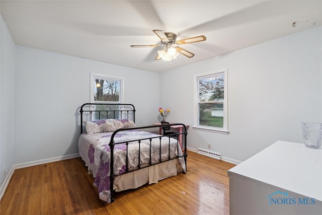 bedroom with multiple windows, ceiling fan, and hardwood / wood-style flooring