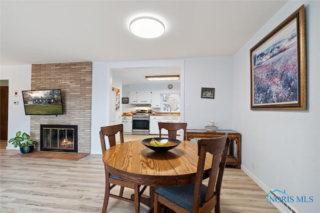 dining space featuring light hardwood / wood-style floors and a brick fireplace