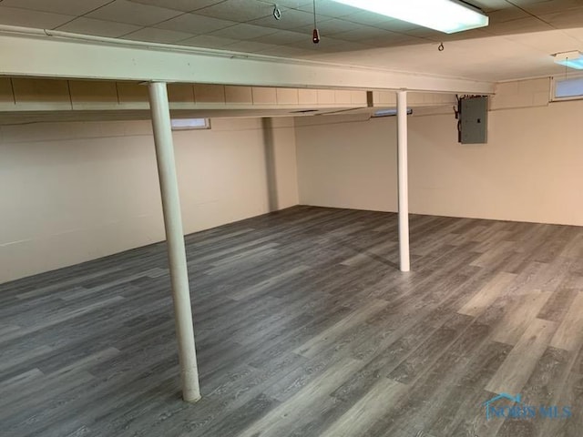 basement with dark hardwood / wood-style flooring and electric panel