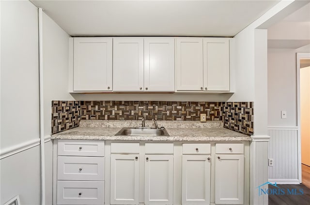 kitchen with white cabinets, decorative backsplash, wood-type flooring, and sink