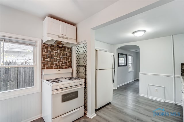 kitchen with decorative backsplash, white cabinetry, wood-type flooring, and white appliances