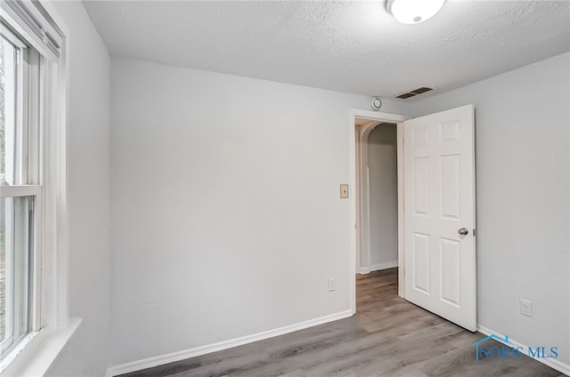 unfurnished room with plenty of natural light, a textured ceiling, and light hardwood / wood-style flooring