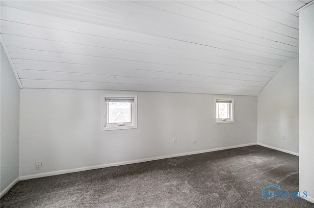 additional living space featuring dark carpet, lofted ceiling, and a wealth of natural light