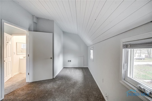 additional living space with dark carpet, vaulted ceiling, and wooden ceiling