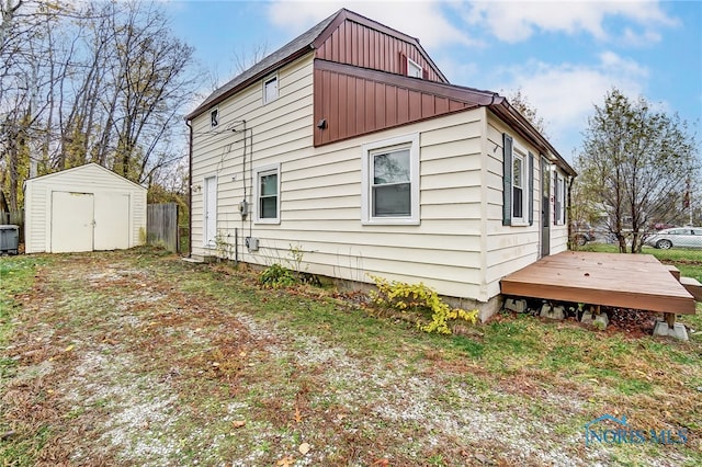 view of side of property featuring a wooden deck and a shed