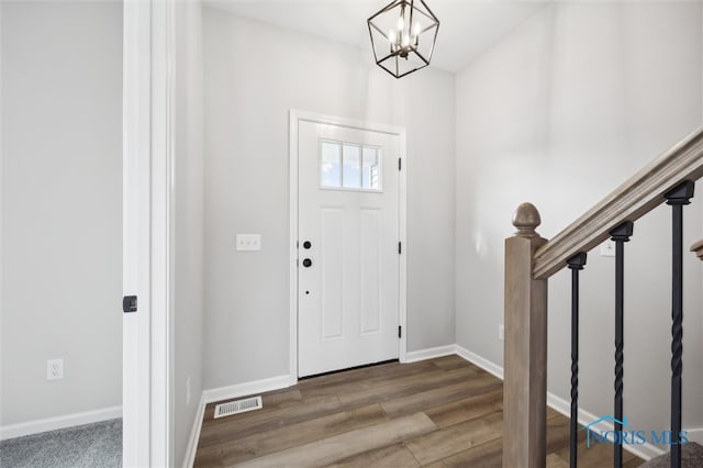 foyer entrance with hardwood / wood-style floors and an inviting chandelier