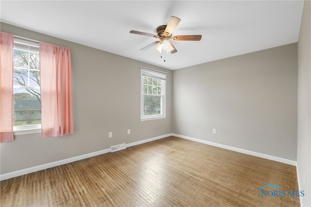 spare room featuring ceiling fan, plenty of natural light, and wood-type flooring