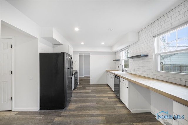 kitchen with dark wood-type flooring, white cabinets, black fridge, stainless steel dishwasher, and butcher block counters