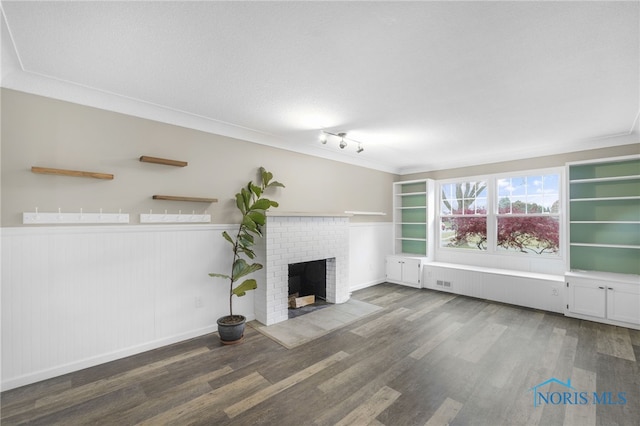 unfurnished living room featuring dark hardwood / wood-style floors, crown molding, and a brick fireplace