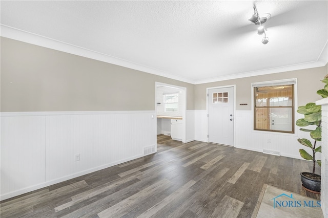 foyer with ornamental molding, a wealth of natural light, and dark wood-type flooring